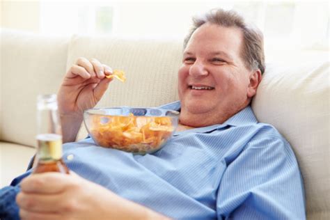 Overweight Man At Home Eating Chips And Drinking Beer Stock Photo ...