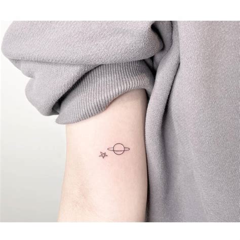 Minimalistic style star and Saturn tattoo located on