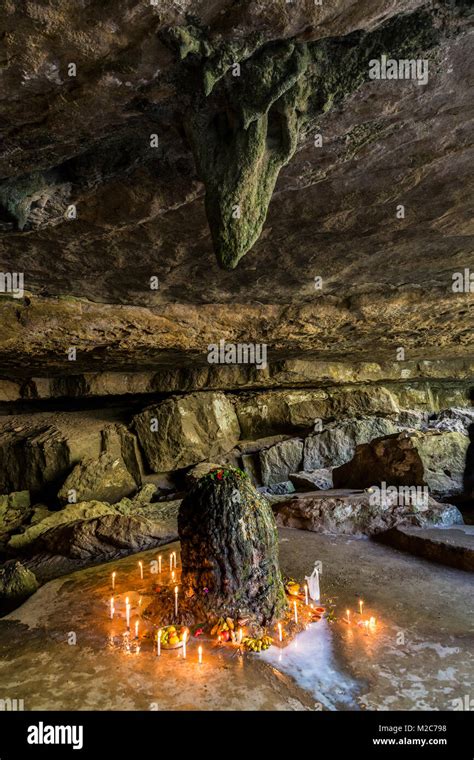 Candles and offerings around stalagmite in holy cave, Mawjymbuin Cave ...