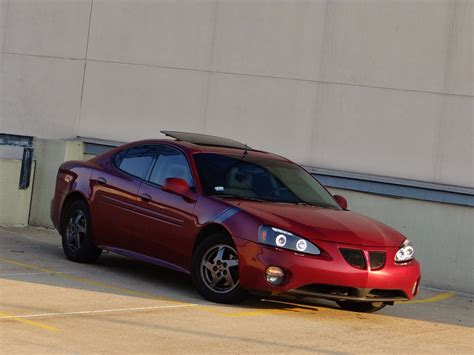 a red sports car parked in a parking lot next to a concrete wall and ...