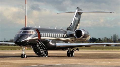 a silver and black jet sitting on top of an airport tarmac with clouds ...