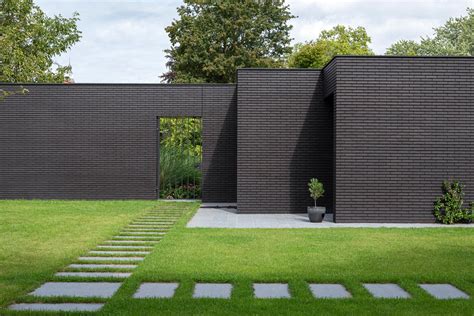 This Home Combines A Black Brick Exterior With Large Glass Walls For A ...