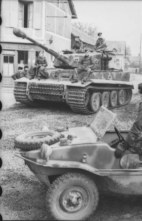 A Tiger I of the 1st SS Panzer Division drives through a French village ...