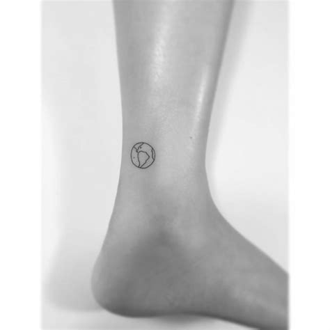 Tiny minimalistic planet Earth tattoo located on the