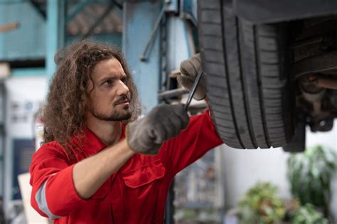 Premium Photo | Car mechanic man in red uniform using spanner to ...