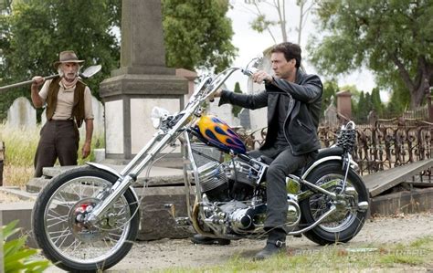 the man is sitting on his motorcycle drinking from a wine glass while ...