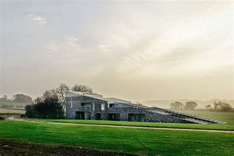 a large house sitting on top of a lush green field next to a dirt road