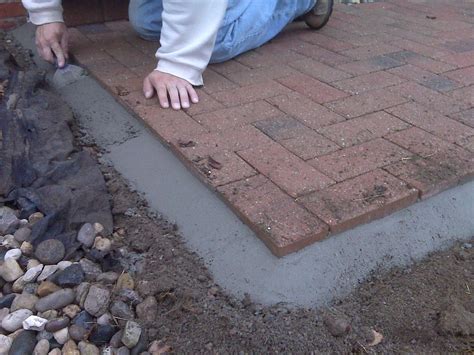 a man laying on top of a brick walkway next to a pile of rocks and gravel