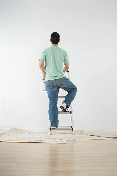 Man climbing a ladder with paint can to paint a wall - StockFreedom ...