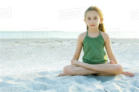 Girl sitting cross-legged on beach, full length - Stock Photo - Dissolve