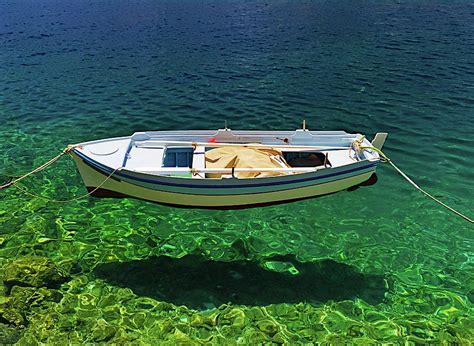 Boat floats on crystal clear water. Photograph by Kostas Pavlis - Fine ...