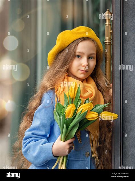 Portrait of a happy girl with a bouquet of yellow tulips on a walk in ...