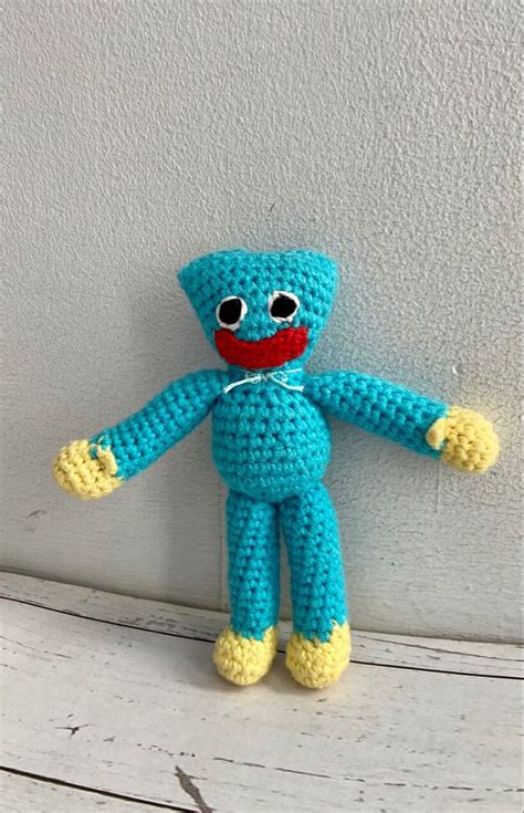 a crocheted blue stuffed animal sitting on top of a wooden table next ...