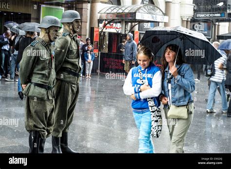 Nazi Zombies stand in the rain as people walk past with umbrellas in ...