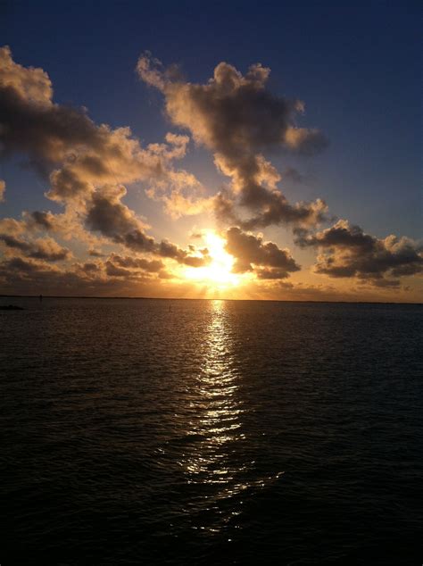 the sun is setting over the ocean with clouds in the sky and water ...