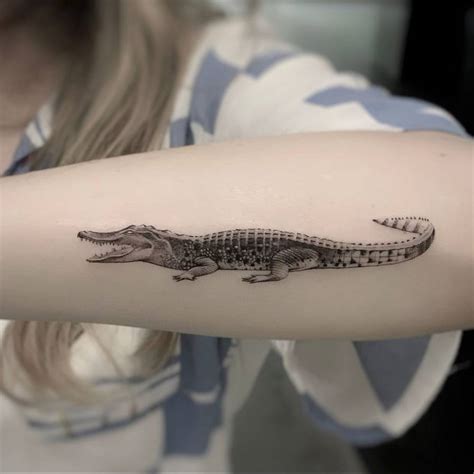 Micro-realistic crocodile tattoo on the forearm.