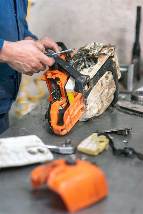 Mechanic repairing a chainsaw. Man repairing a chainsaw in workbench ...