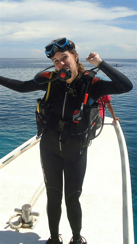 a woman in scuba gear standing on the side of a boat