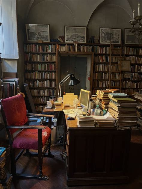 Desk with a lamp lighting up the surrounding piles of books lining the ...