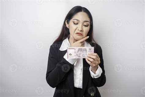 A thoughtful young woman is wearing black suit and holding cash money ...