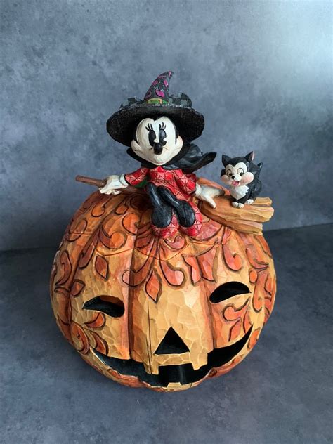 a mickey mouse figurine sitting on top of a pumpkin with a black cat