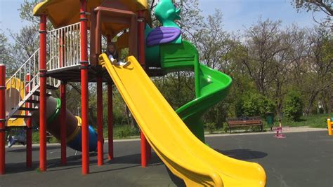 Child Sliding On A Slide In Park, Little Girl Playing At Playground ...