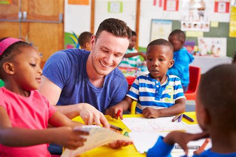 Volunteer Teacher Sitting With Preschool Kids In A Classroom Stock ...