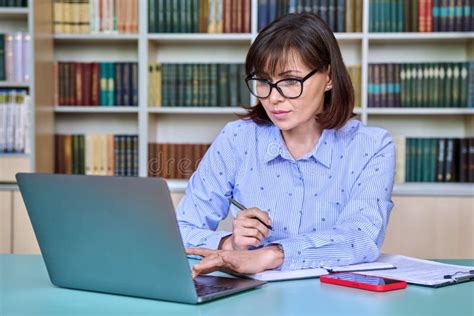 Middle-aged Female Teacher Working in Library, Using Laptop Stock Image ...