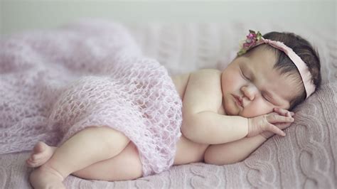 cute baby girl is sleeping on bed covered with netted cloth and having ...