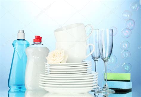 Empty clean plates, glasses and cups with dishwashing liquid and ...