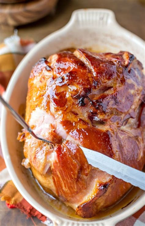 a cooked ham in a white bowl with a knife