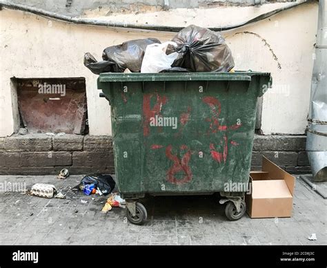 Green dirty trash dumpster, front view, next to the wall of the old ...