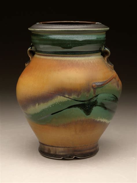 a brown and green vase sitting on top of a table