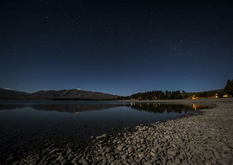 Lake Tekapo at night. Stars above the perfect smooth lake surface and ...