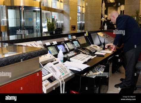 Security Guard at the control desk with phones and monitors in highrise ...