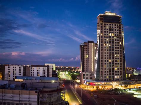 the city skyline is lit up at night with buildings in the foreground ...