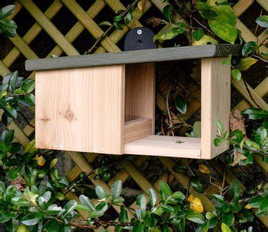 a bird house built into the side of a wooden fence with green leaves ...