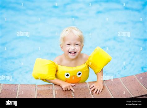 Baby in swimming pool with yellow swim aid. Child with float wings. Kid ...