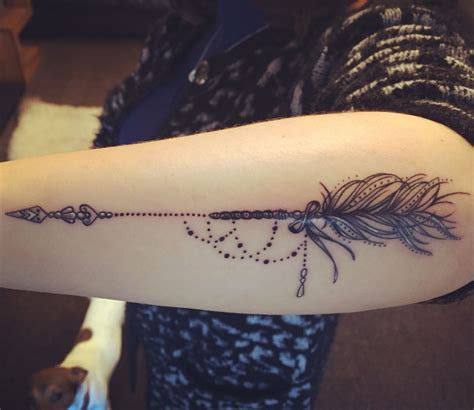 a woman's arm with a feather and beads tattoo on the left side of her arm