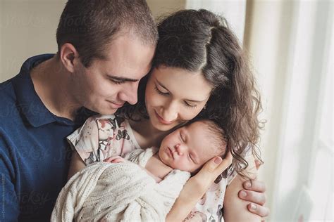 "Proud Parents Holding And Snuggling With Their Newborn Baby" by ...