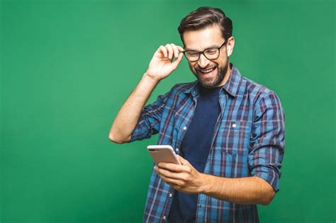 Premium Photo | Smiling young man holding smart phone and looking at it ...