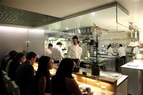 a group of people sitting at a table in front of a restaurant counter ...