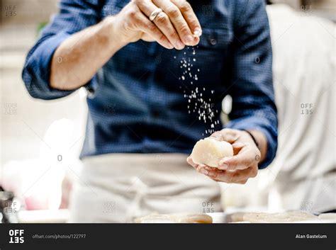 Chef sprinkling salt over a scallop stock photo - OFFSET