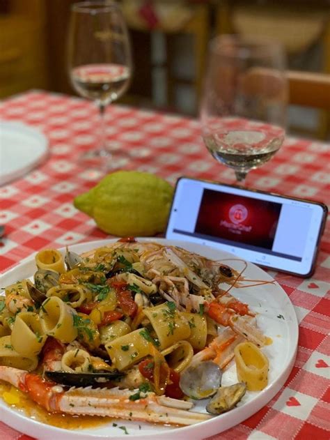 a white plate topped with pasta and veggies next to a cell phone on a ...