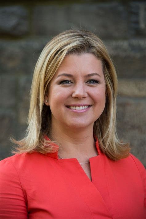 a woman in a red shirt is smiling for the camera and she has blonde hair