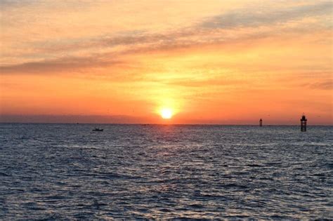 Premium Photo | A sunset over the ocean with a lighthouse in the background