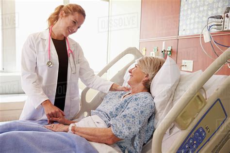 Female doctor talks to senior female patient in hospital bed - Stock ...