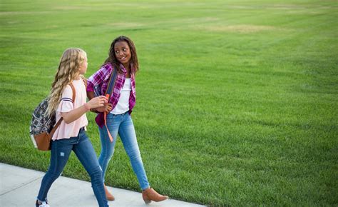 Two diverse school kids walking and talking together on the way ...