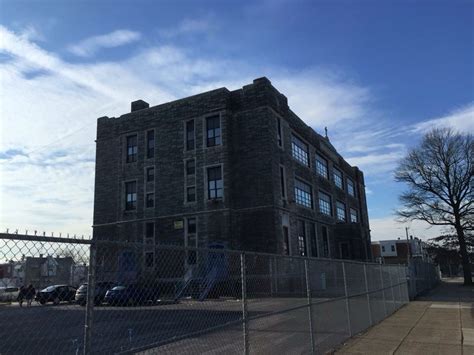 an old brick building behind a chain link fence