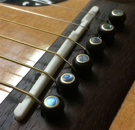 Snazzy ebony, abalone, brass guitar bridge pins add the finishing touch ...